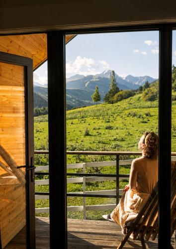 a woman sitting in a chair on a porch looking out a window at Ayu Eco Hotel in Karakol