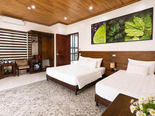 a hotel room with two beds and a desk at Daisy's Villa TamCoc in Ninh Binh