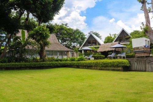 a house with a large lawn in front of it at Chanteak Bali in Jimbaran