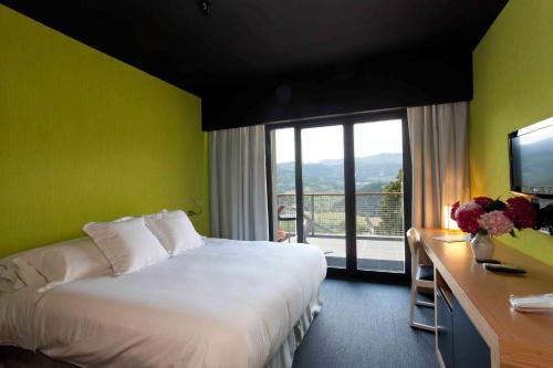 a hotel room with a bed and a desk with a television at Grupo Izarbe, HOTEL ELLAURI in Zeanuri