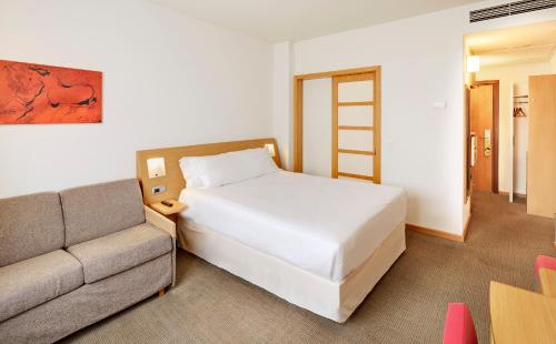 a hotel room with a bed and a couch at Sercotel Valladolid in Valladolid