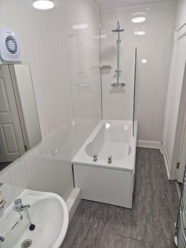 a white bathroom with a sink and a tub at The Coastal Inn OUTBUILDING in Cellardyke