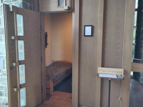 a door to a small room with a bed in it at Herbergskirche Gleidorf in Schmallenberg