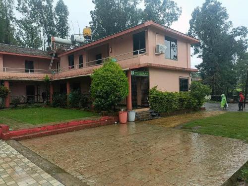a house in the rain with people walking in front of it at Collection O Parsi Point Mahabaleshwar Formerly Jungle Eye in Mahabaleshwar