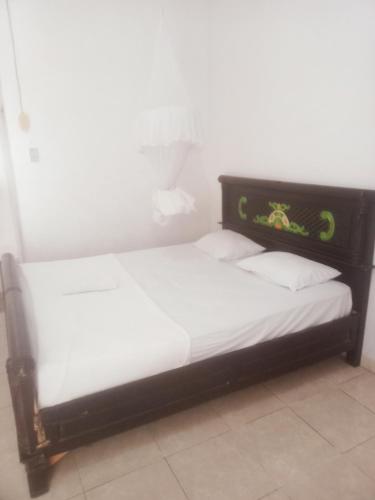 a bed with a black frame and white sheets and pillows at Obama homestay in Riung