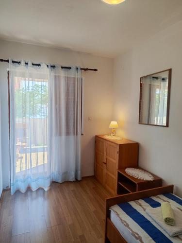 a bedroom with a bed and a window at Apartman Olja in Pag