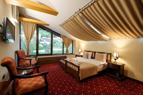 a bedroom with a bed and a chair in a room at Classic Inn Hotel in Braşov