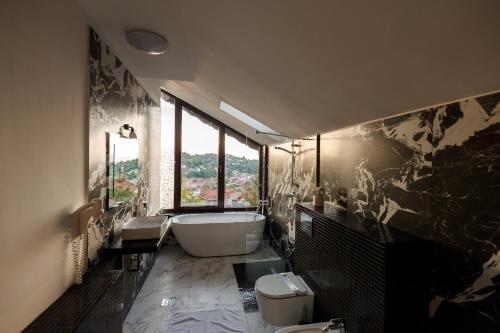 a bathroom with a bath tub and two toilets at Classic Inn Hotel in Braşov