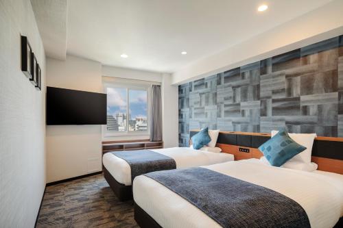 a hotel room with two beds and a tv at HOTEL MYSTAYS Nagoya Sakae -Renewed in September 2026 All Guest Rooms & Breakfast in Nagoya