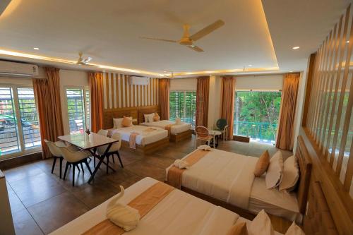 a hotel room with two beds and a table and chairs at Adrivana Hospitality By The Stream in Padinjarathara