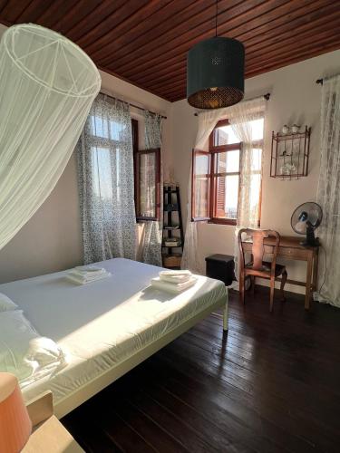 a bedroom with a bed and a desk and windows at The Stone House in Maronia