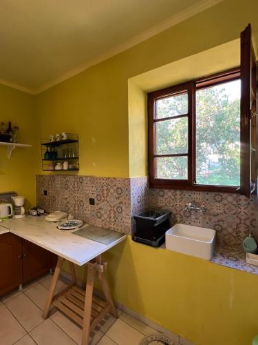 a yellow kitchen with a counter and a window at The Stone House in Maronia