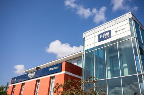 a glass building with a sign on the side of it at Elema Hotels Beauvais ex Hostellerie Saint Vincent Beauvais Aeroport in Beauvais