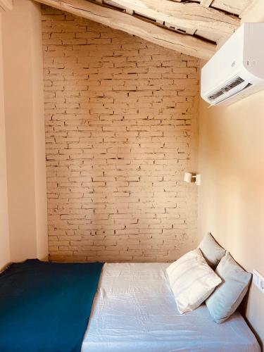 a bed in a room with a brick wall at Buhardilla con encanto in Ontinyent