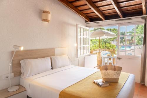 a bedroom with a bed with a table and a window at RVApartaments Escala Brava in L'Escala