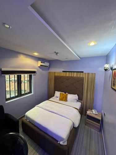 a bedroom with a large bed with blue walls at Clisamnoris Hotel limited in Diobu