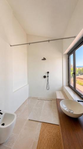 a white bathroom with a sink and a shower at Almarìa - Le case del Castello - San Nicola L'Arena - Trabia in Trabia