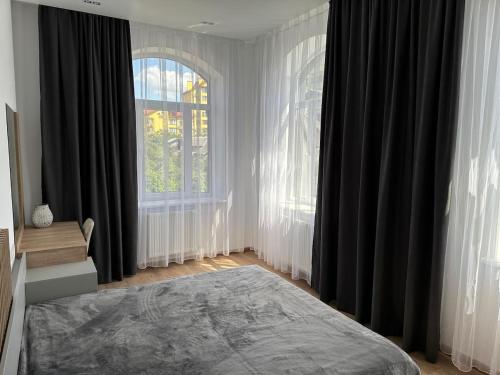 a bedroom with black curtains and a bed and a window at Апарт-готель номер 303 in Truskavets