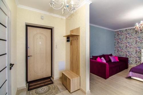 - un salon avec un canapé violet et une porte dans l'établissement Apartments Promenade Expo, à Astana
