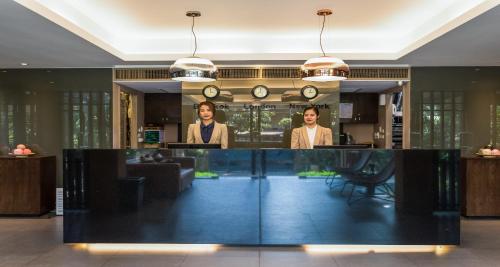 two people standing behind a counter in a lobby at The Cottage Suvarnabhumi in Lat Krabang