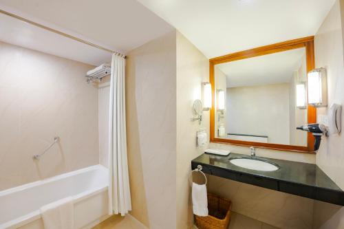 a bathroom with a sink and a tub and a mirror at MGM Mark Whitefield in Bangalore