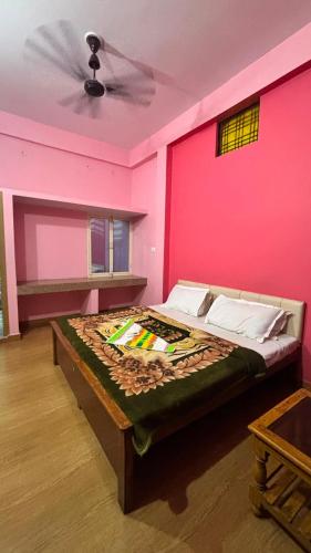a bedroom with a pink wall with a bed at Hotel Ashirwad in Chhatarpur