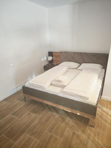 a bed with white sheets and a wooden floor at Terra Residence Beiuș in Beiuş