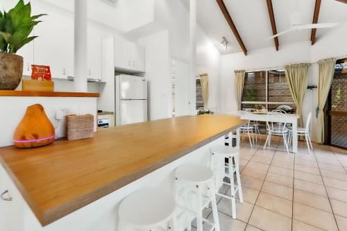 a kitchen with white walls and a counter with stools at Green Cottage Trinity Beach Pet friendly BBQ in Trinity Beach