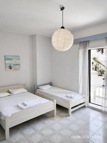 two beds in a room with a window and a chandelier at Galatas home in Galatas
