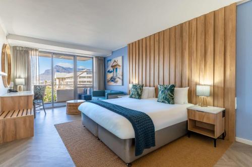 a bedroom with a large bed and a large window at Lagoon Beach Hotel & Spa in Cape Town