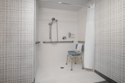 a shower stall with a chair in a bathroom at Hampton Inn Terre Haute in Terre Haute