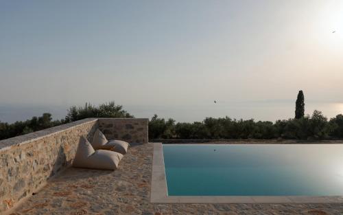 a swimming pool with two pillows next to a stone wall at Pirgos Petropoulea in Poliána