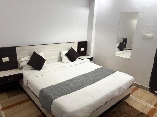 a bedroom with a large white bed with a mirror at Grand Almada Inn in Lucknow
