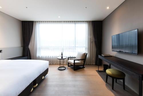 a hotel room with a bed and a desk and a television at Hotel Nanta Jeju in Jeju