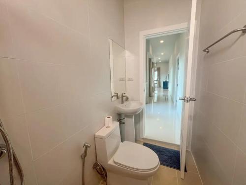 a white bathroom with a toilet and a sink at Indigo Garden Villa by Somjai in Ban Tha Fat
