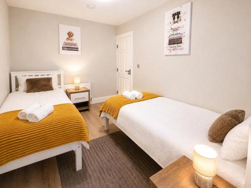 two beds in a small room with white and yellow sheets at The Viking Townhouse - Heart of Waterford in Waterford
