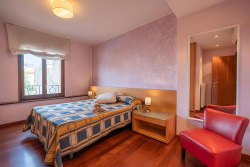 a bedroom with a bed and a red chair at Can Jeroni in Figueres