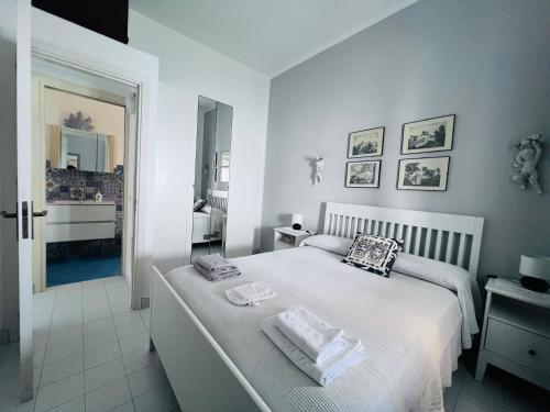 a white bedroom with a bed and a bathroom at Le casette di nonna Giulia B in Lingua