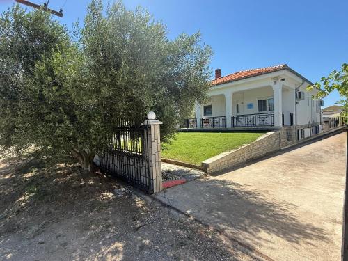 a fence in front of a house with a tree at My House in Paralia Messi in Aroyí