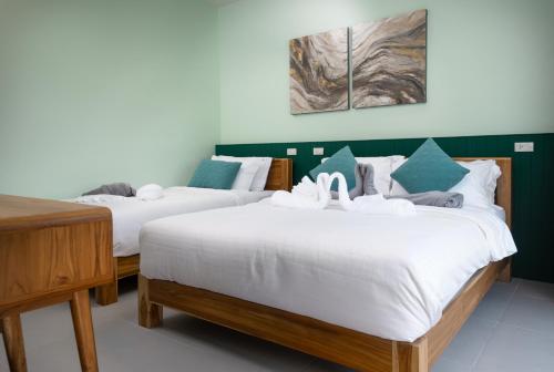 two beds in a room with green walls at Turtle Tales - Tao Yaa in Thai Muang