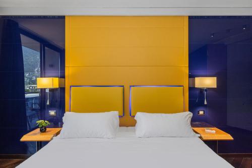 a bedroom with a large bed with a yellow headboard at Garda Suite Hotel - Tonelli Hotels in Riva del Garda