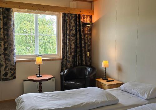 a room with two beds and a chair and a window at Idrettsparken in Røros