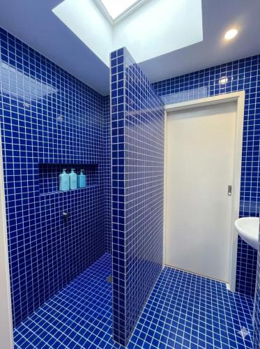 a blue tiled bathroom with a white door at The Bluff Shack in Wye River
