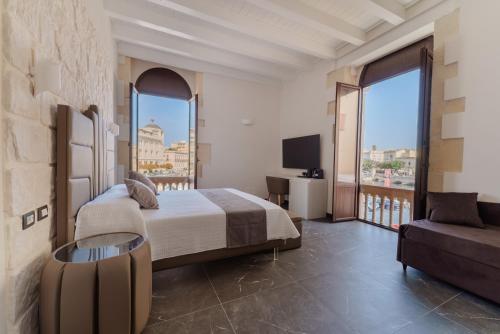 a bedroom with a bed and a balcony with a tv at La Finestra sul Mare di Ortigia Suite Luxury in Syracuse