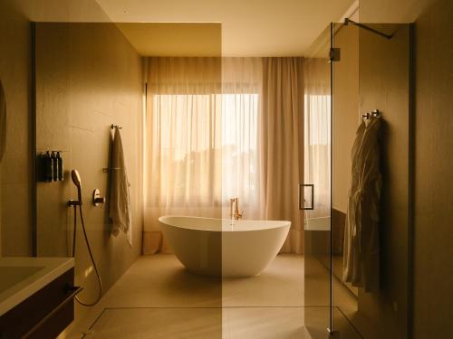 a bathroom with a tub and a window at RIVELIAN Grand Menorca in Menorca
