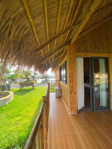 a porch of a wooden house with a grass roof at Dung Hoa Resort 
