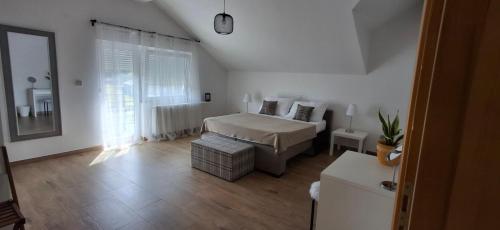 a white bedroom with a bed and a window at Villa Sorella Baranja in Karanac