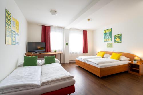 a living room with two beds and a television at SLEEEP Hotel Sattledt in Sattledt