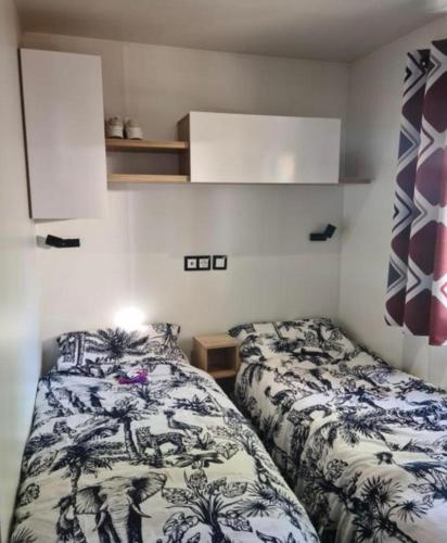 two beds in a small room with a bedskirtsermottermott at Floriane in Claouey