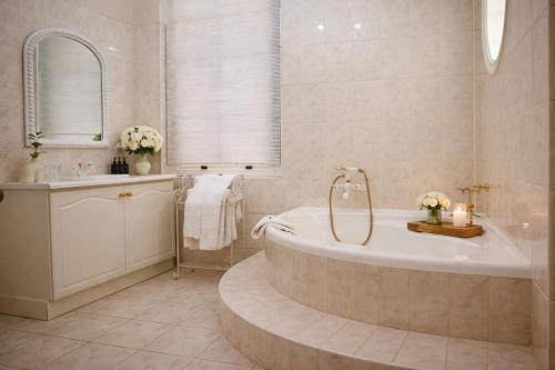 a bathroom with a tub and a sink and a mirror at Bakenskraal Ostrich Palace in Oudtshoorn